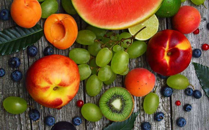 frutta su uno sfondo di legno, pesche, uva, albicocche, kiwi