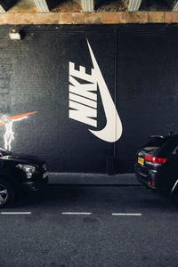 a black car parked in front of a nike wall nike wallpaper