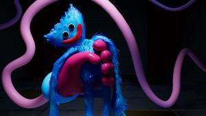 a blue and purple stuffed animal is sitting in a dark room poppy playtime wallpaper