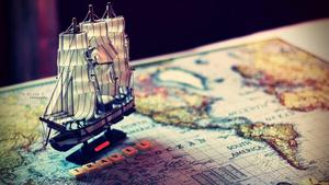 A boat sails across the globe world map wallpaper