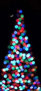 a christmas tree with colorful lights in the background Wallpaper