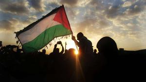 a man holds up a palestinian flag in the sun palestine wallpaper