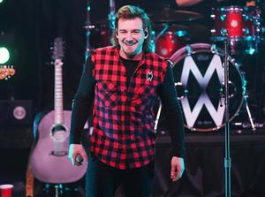 a man in a plaid shirt is smiling on stage Wallpaper
