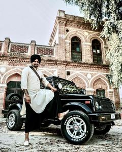 a man in a turban standing next to a jeep Wallpaper