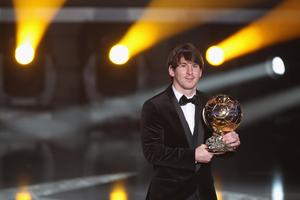 a man in a tuxedo holding a trophy messi wallpaper