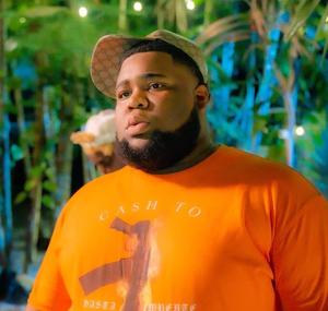 a man in an orange shirt standing in front of a tree rod wave wallpaper