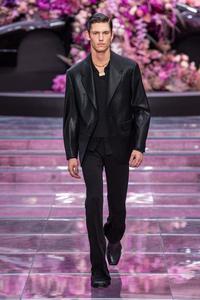 a man in black suits walks down the runway Wallpaper