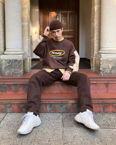 a man sitting on steps wearing a brown sweatshirt and hat Wallpaper