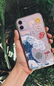 a person holding a phone case with stickers on it Wallpaper