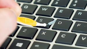 a person is using a toothbrush to clean a keyboard laptop wallpaper