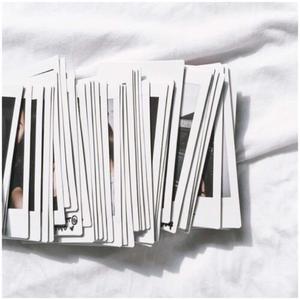 a pile of polaroid photos on a white bed white aesthetic wallpaper