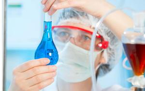a scientist is holding a blue liquid in a glass Wallpaper