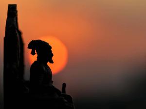 a statue of a man sitting in front of a sunset shivaji maharaj wallpaper