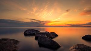 a sunset with rocks and water in the background summer wallpaper