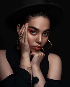 a woman in a black hat with gold jewelry black wallpaper