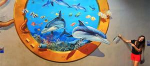 a woman standing next to a mural of dolphins and sea life Wallpaper