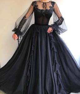 a woman wearing a black dress with lace sleeves black wallpaper