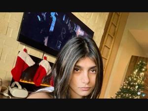 a young girl is sitting in front of a christmas tree mia khalifa wallpaper