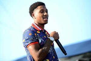 a young man holding a microphone while standing on stage nba youngboy wallpaper