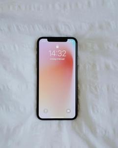 an iphone x is laying on a bed phone wallpaper