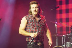 Country music sensation Morgan Wallen looks on with a cowboy hat, denim shirt and a guitar. morgan wallen wallpaper