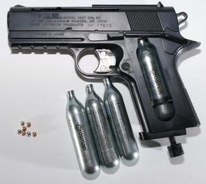 Description- An image of a black gun lying on an army-camo patterned blanket gun wallpaper