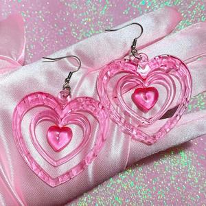 pink heart shaped earrings on a pink silk y2k aesthetic wallpaper