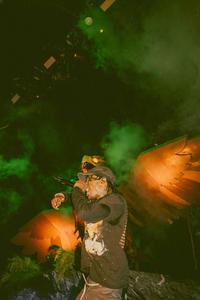 Travis Scott delivering an energetic performance illuminated by yellow and orange flames travis scott wallpaper