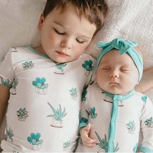 two children sleeping in a bed with cactus plants on the bed matching wallpaper