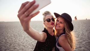 two women taking a selfie on the beach instagram profile wallpaper