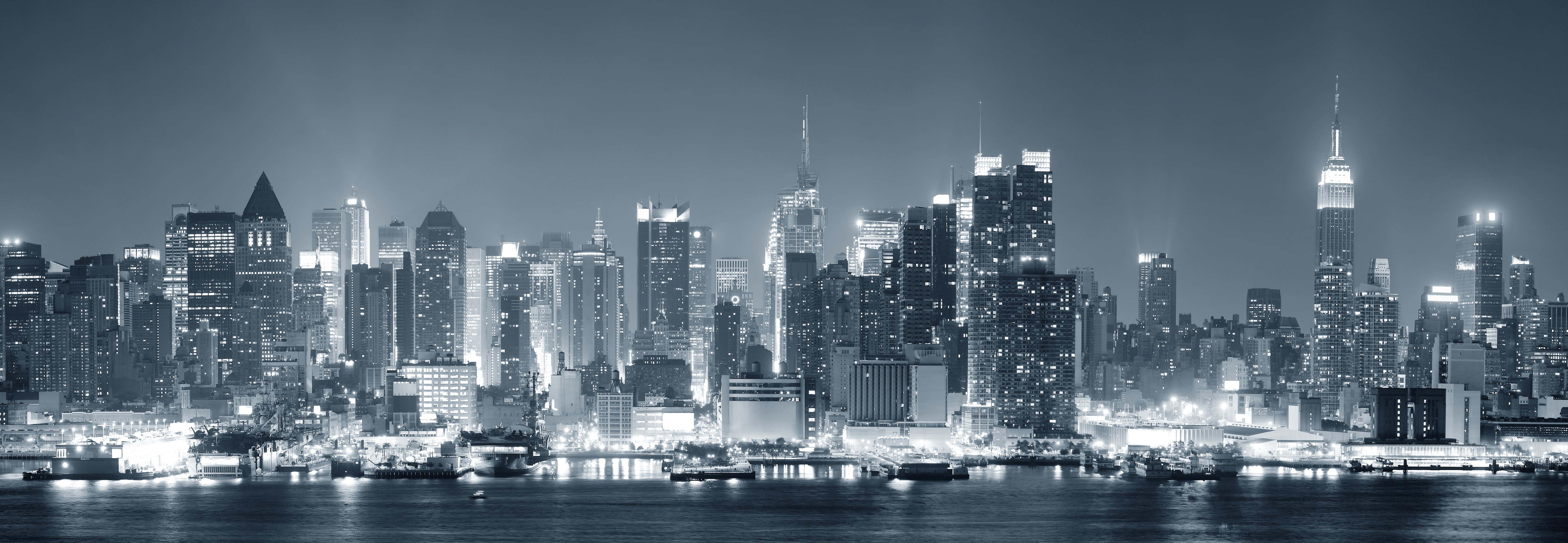 a black and white photo of a city skyline at night — 7397x2564 wallpaper