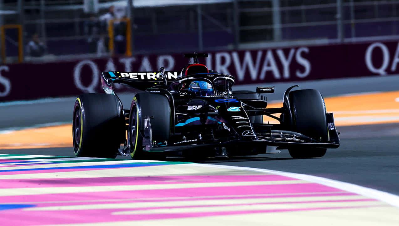 a black racing car driving down a track — 1274x724 wallpaper