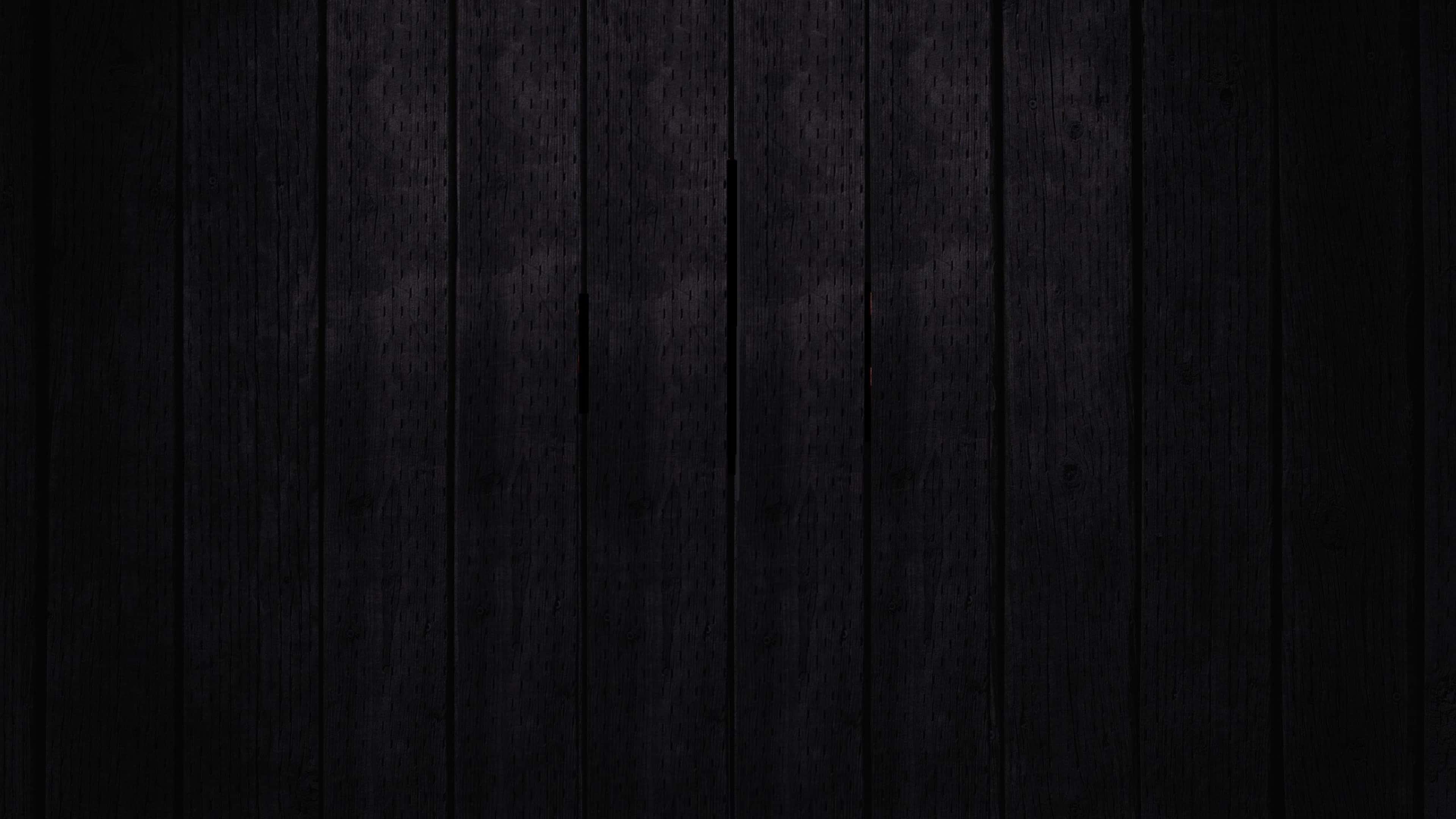 a black wooden background with a light shining on it — 3840x2160 wallpaper