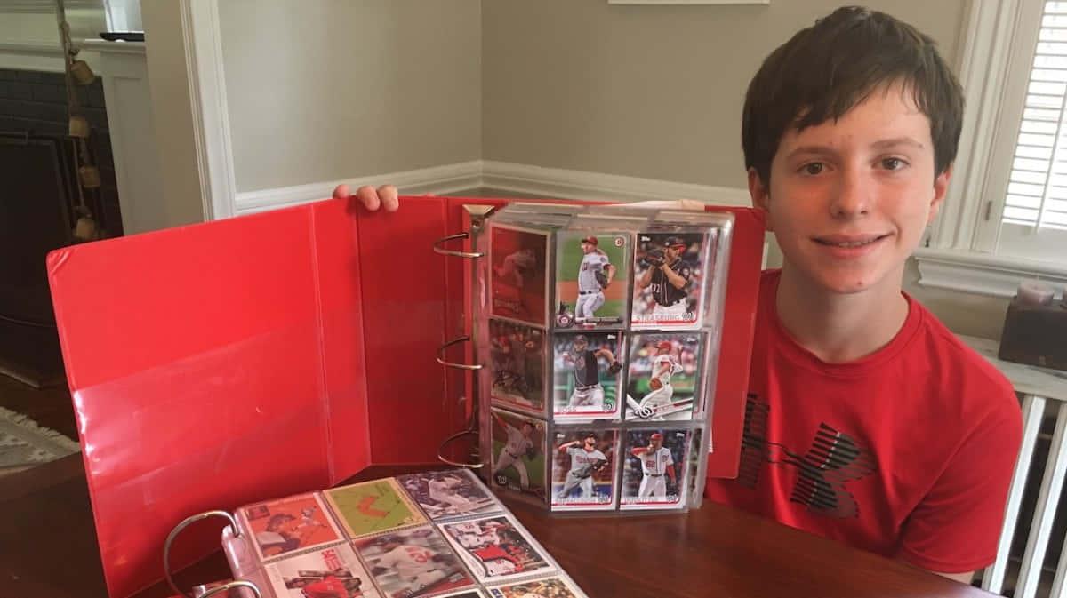 a boy holding a red binder full of cards — 1200x673 wallpaper