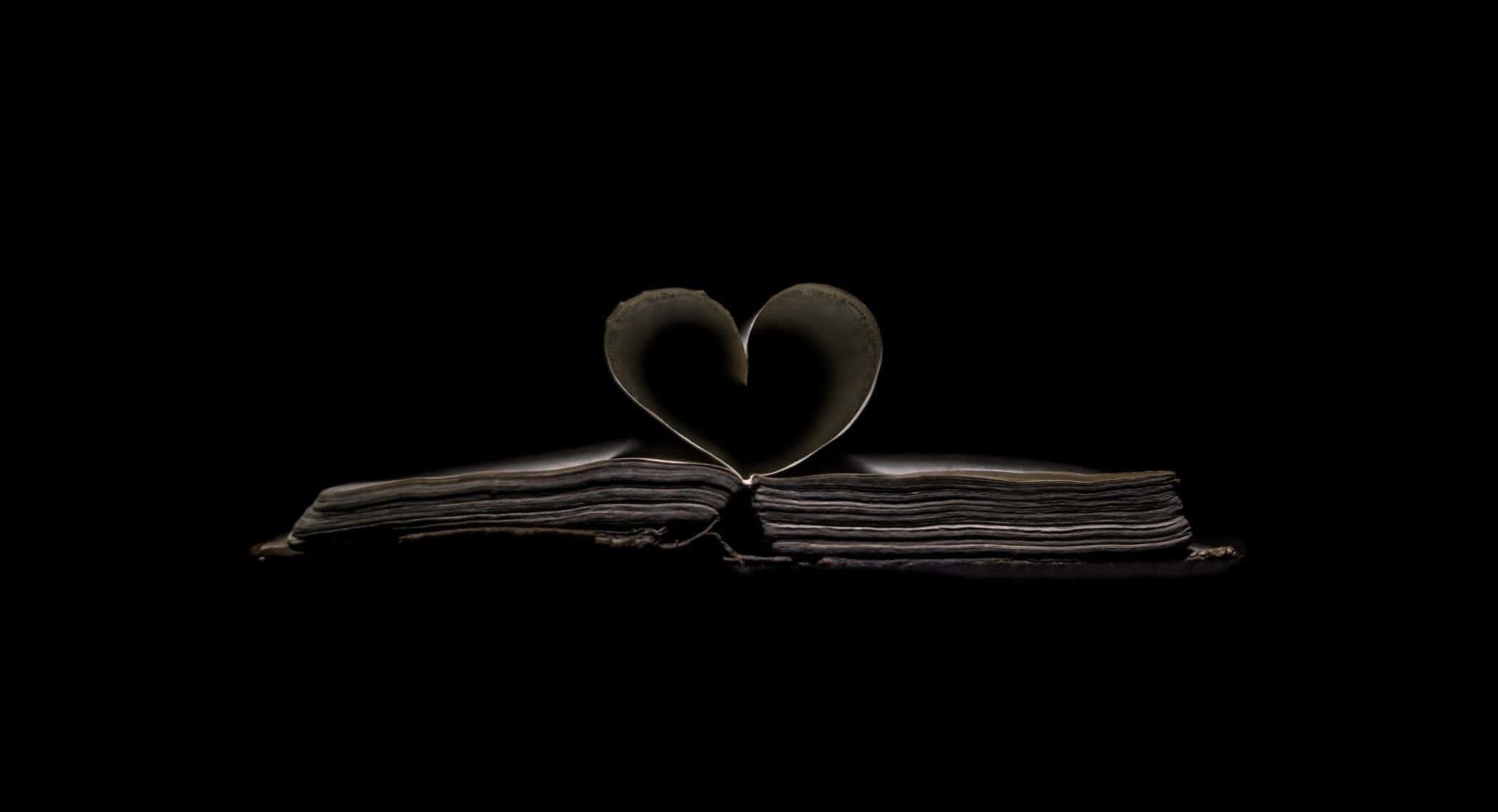 A broken heart shattering into pieces against a dark black background. — 2048x1110 wallpaper