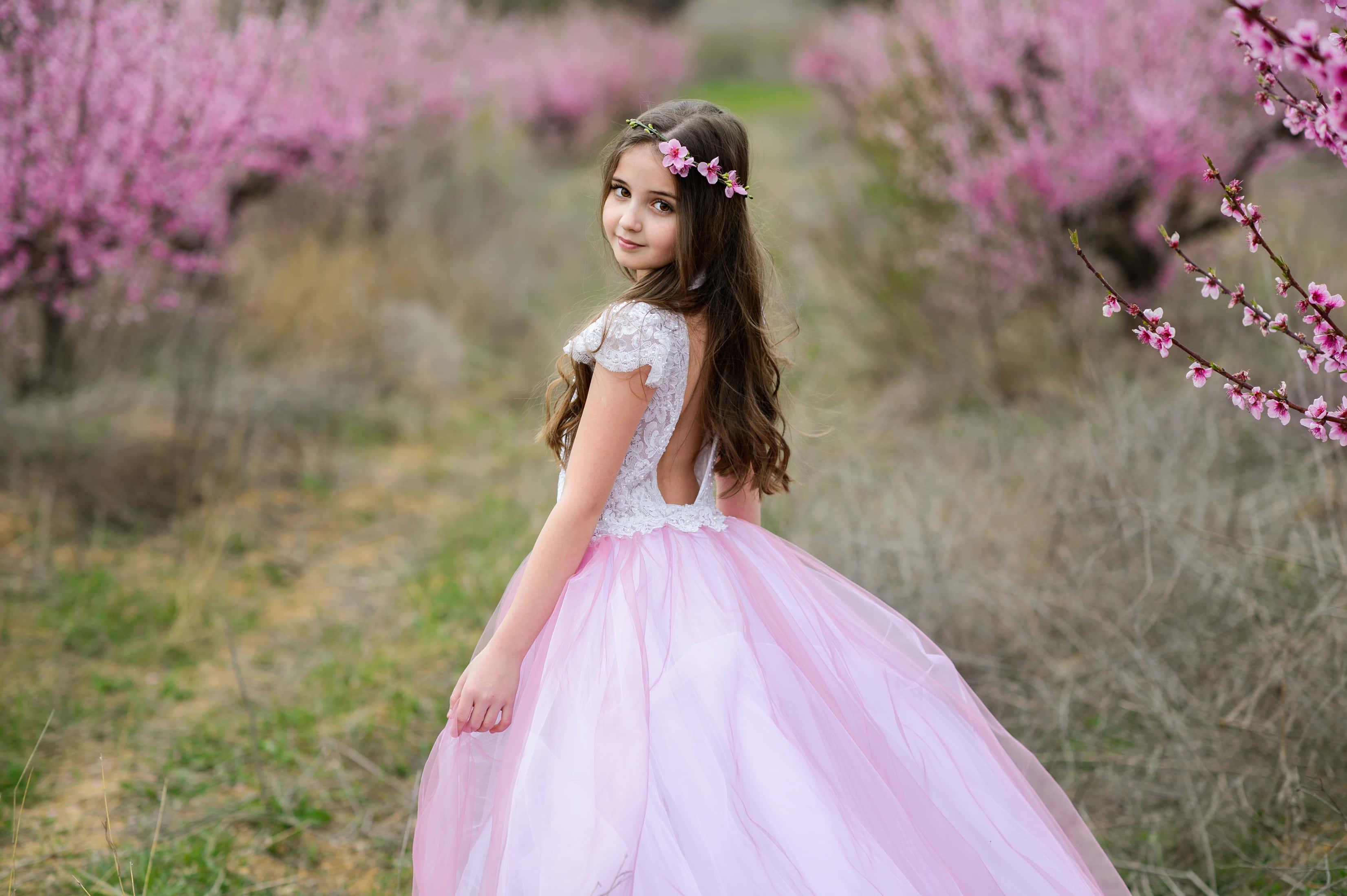 a girl in a pink tulle dress is standing in a field of blossoms — 3305x2200 wallpaper