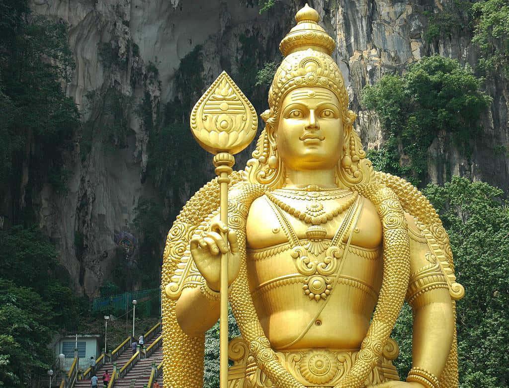 a golden statue of lord shiva in front of a mountain