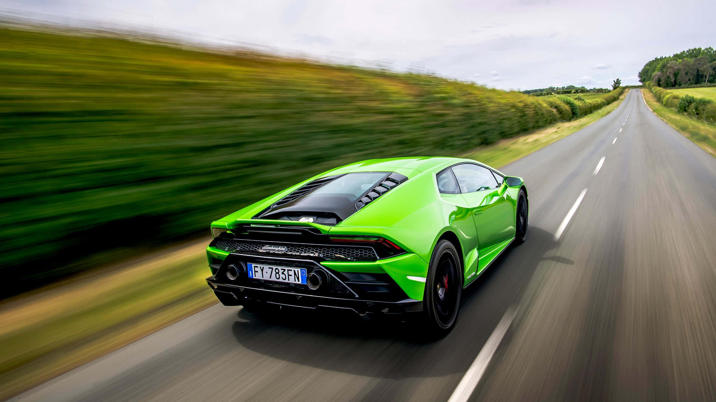 a green sports car driving down a country road — 2400x1350 wallpaper