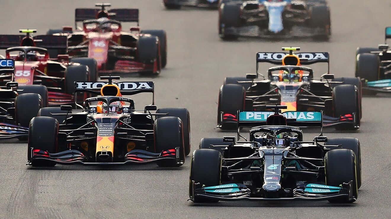 a group of racing cars are racing down a track — 1320x741 wallpaper