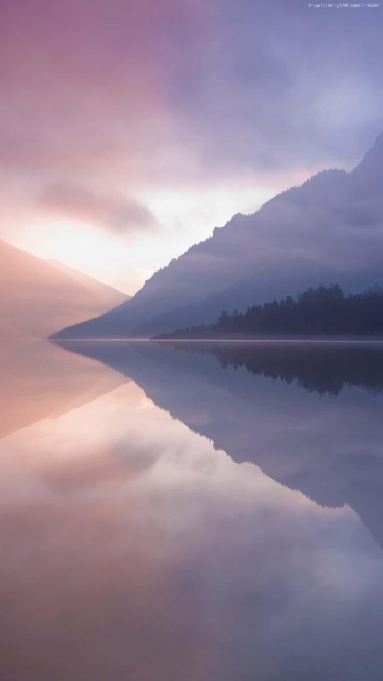 a lake with mountains and fog reflected in it — 1242x2208 wallpaper