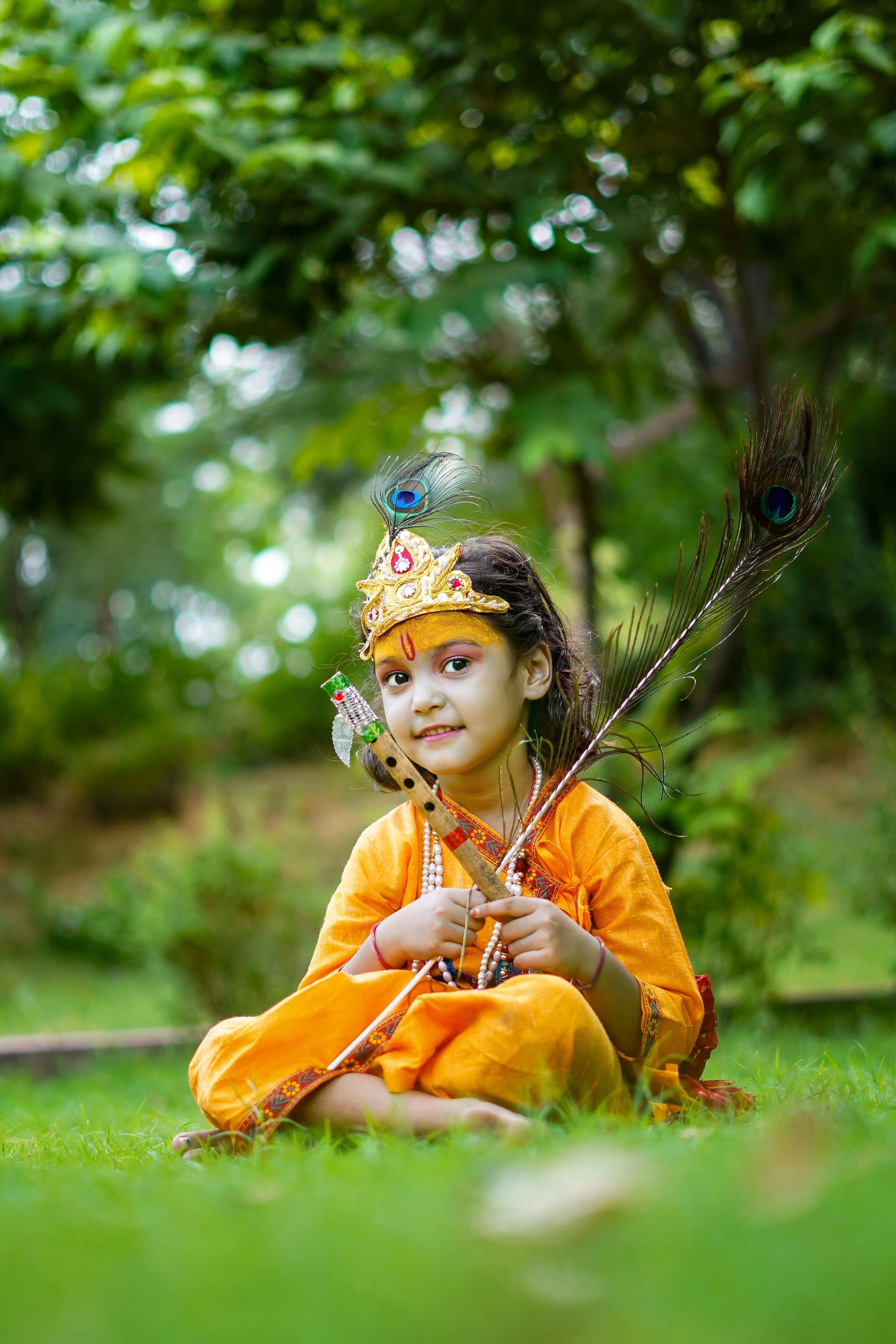 a little girl in orange sitting on the grass