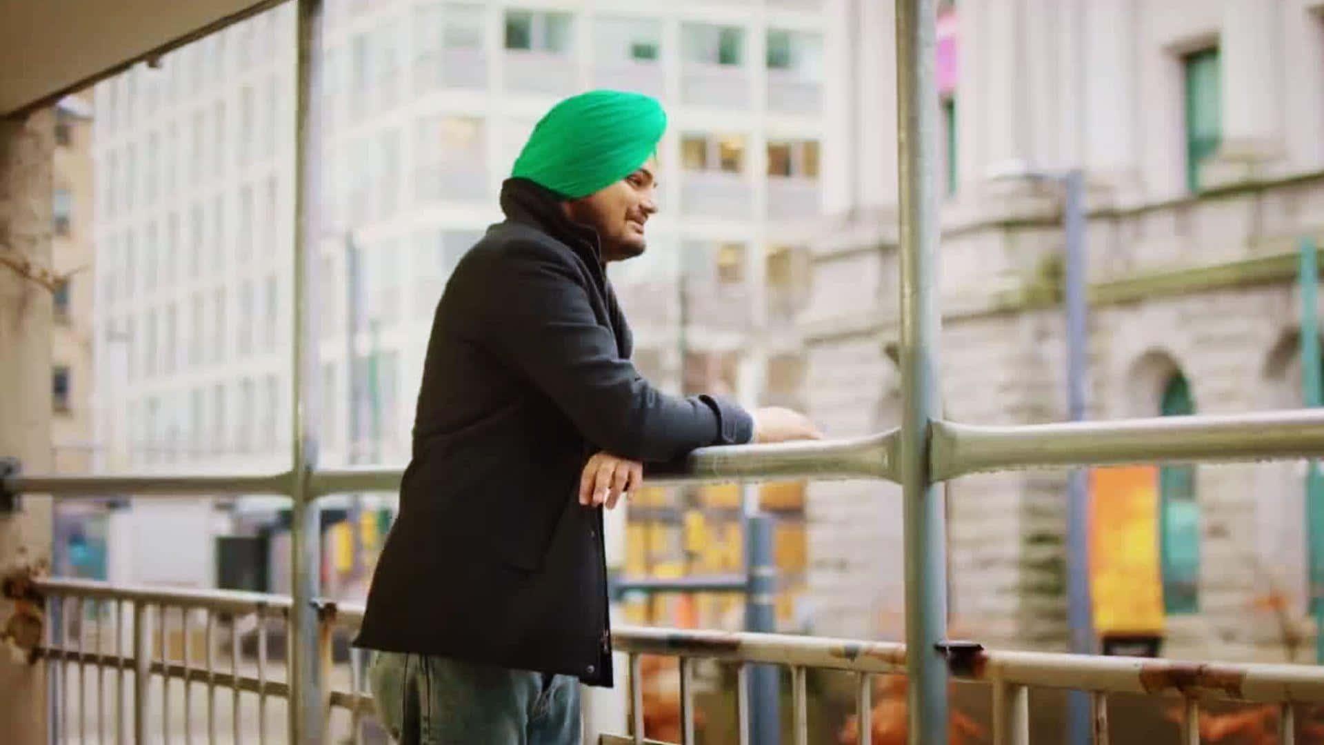 Ein mann mit grunem turban lehnt an einem gelander