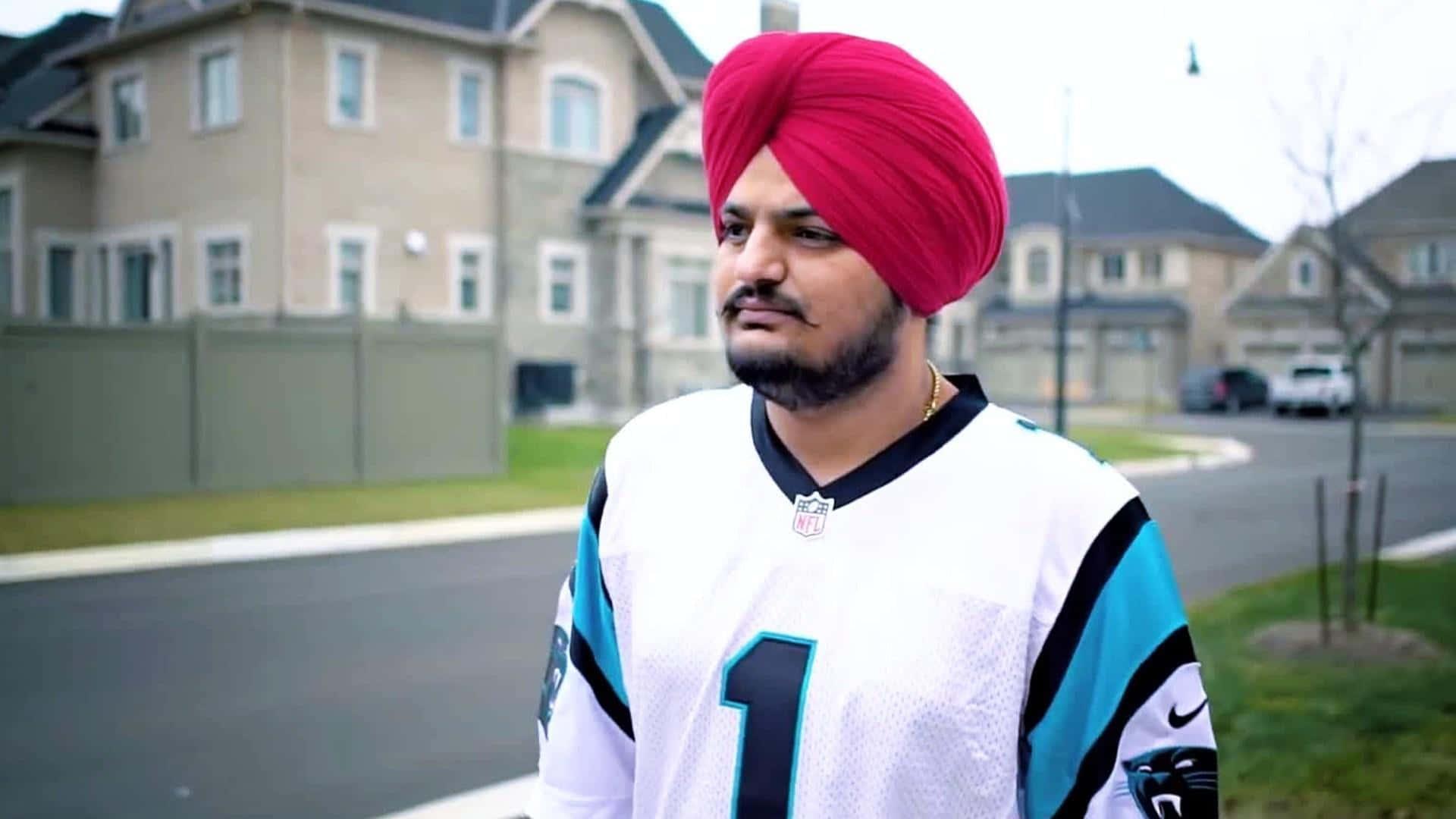 a man in a red turban standing in front of a house