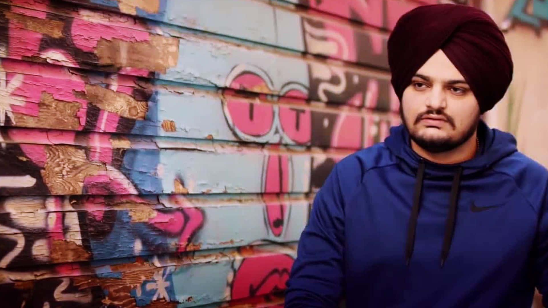 a man in a turban standing in front of graffiti