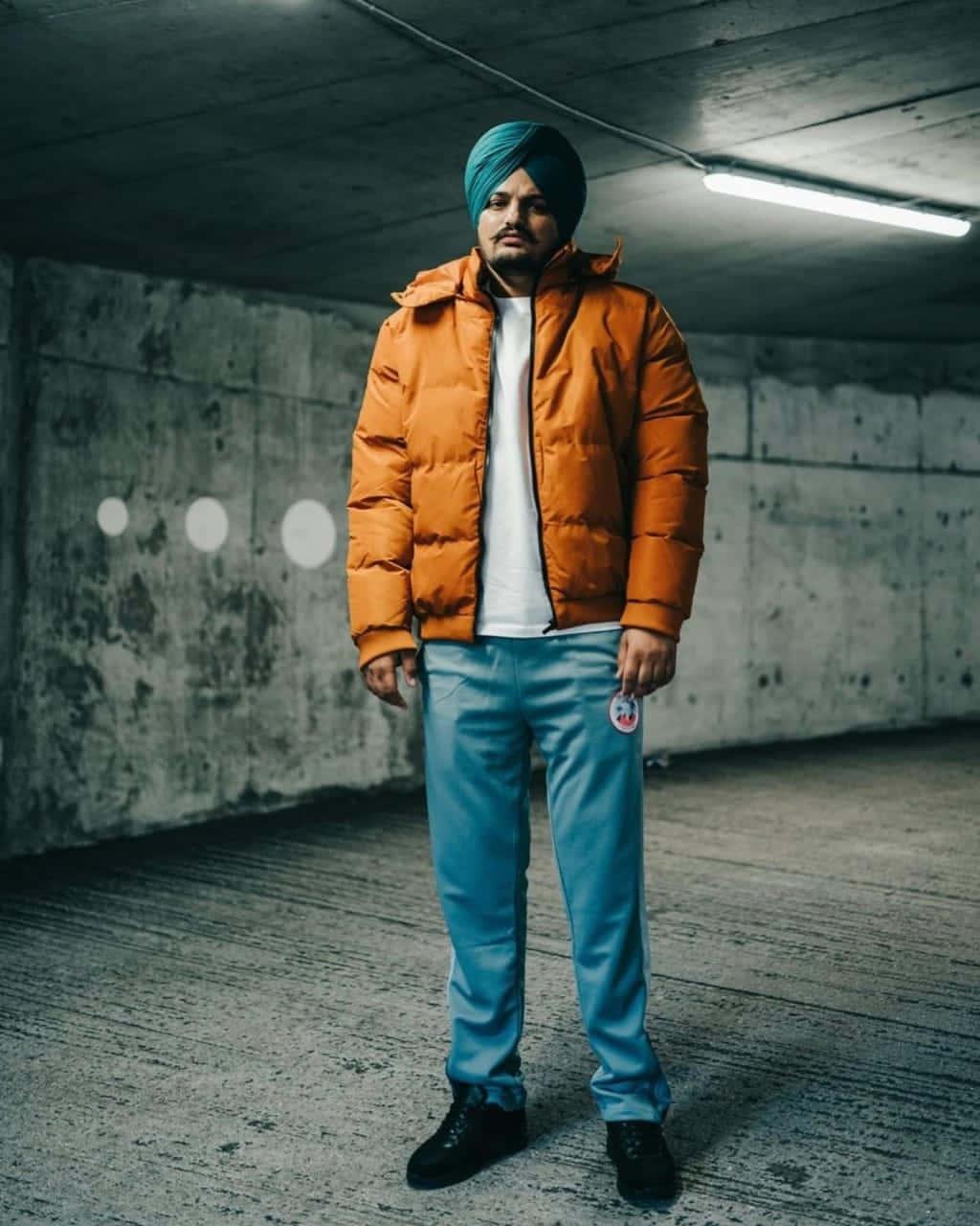 a man in an orange puffer jacket standing in a parking garage