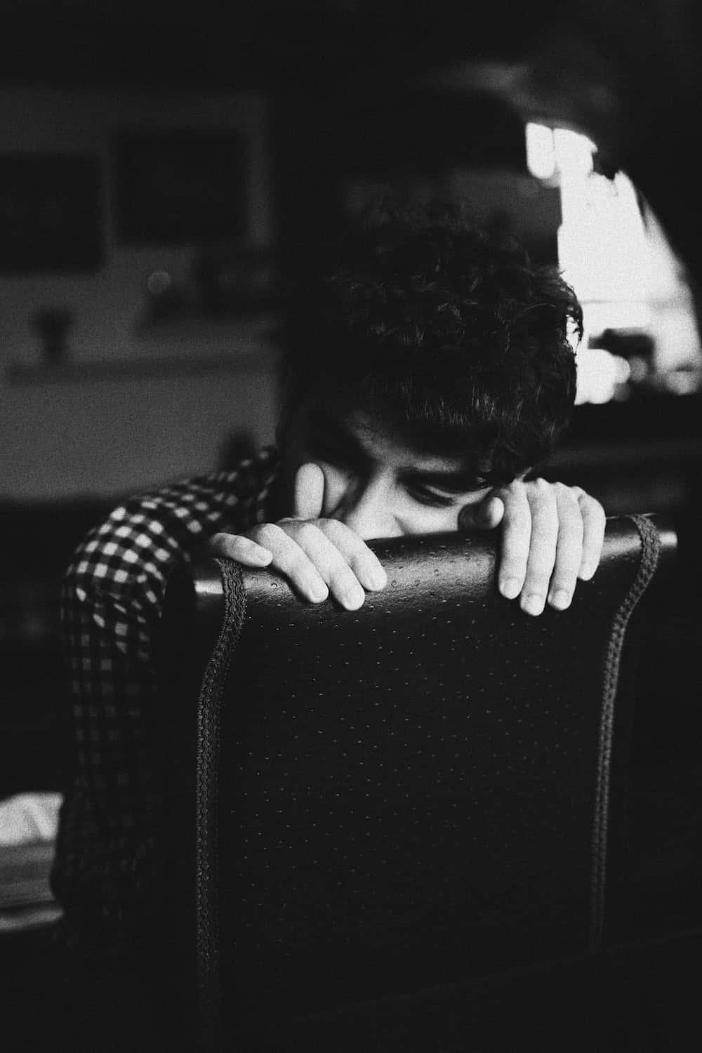a man is sitting on a chair with his hand on his face — 1000x1500 wallpaper