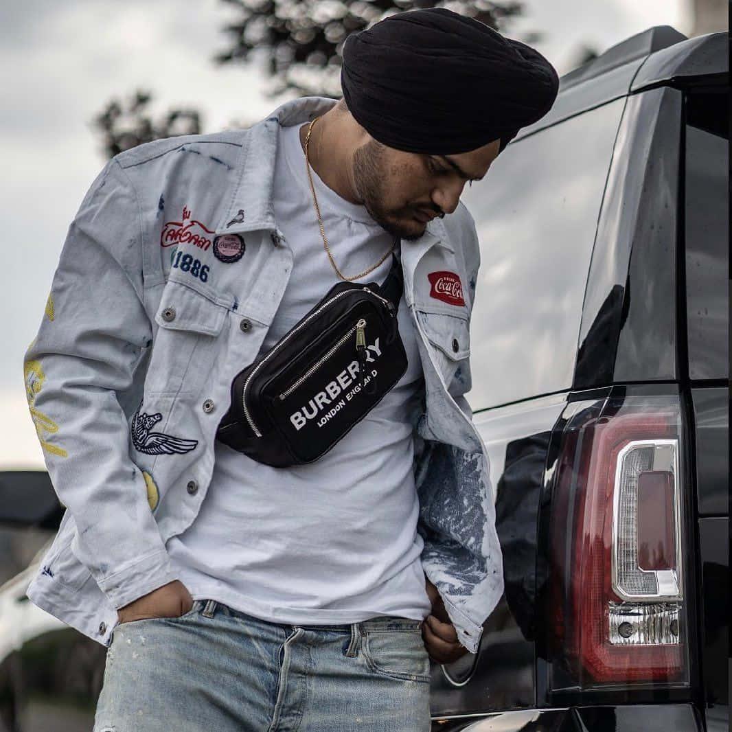 Ein mann mit turban und jeans neben einem auto