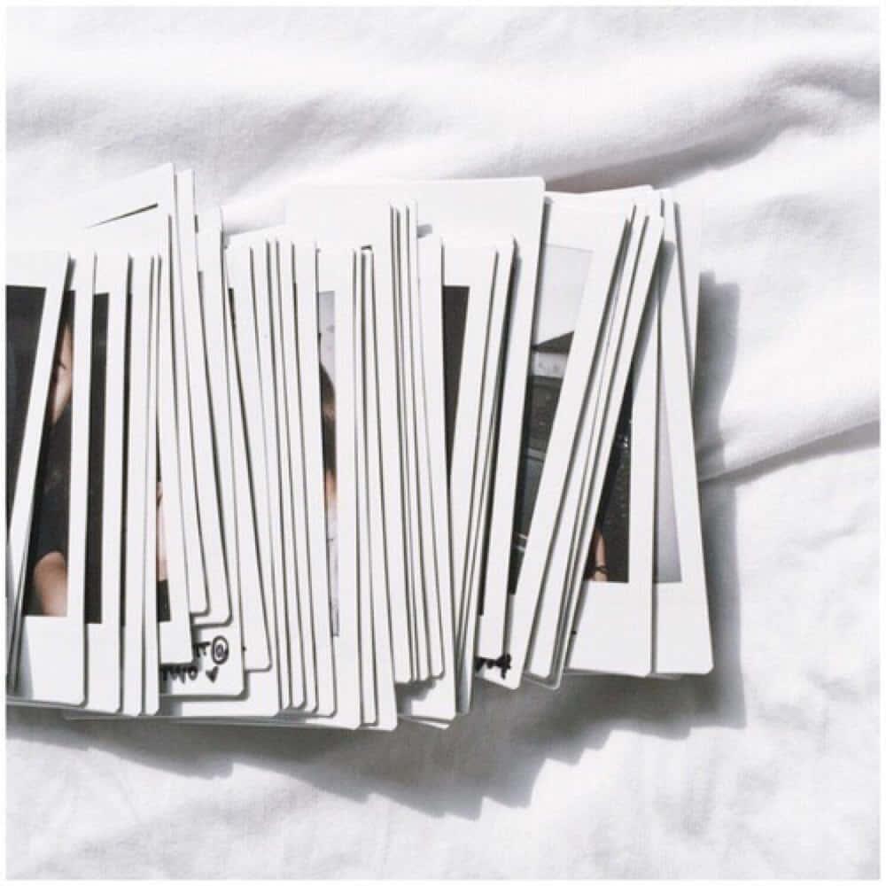 a pile of polaroid photos on a white bed — 1000x1000 wallpaper