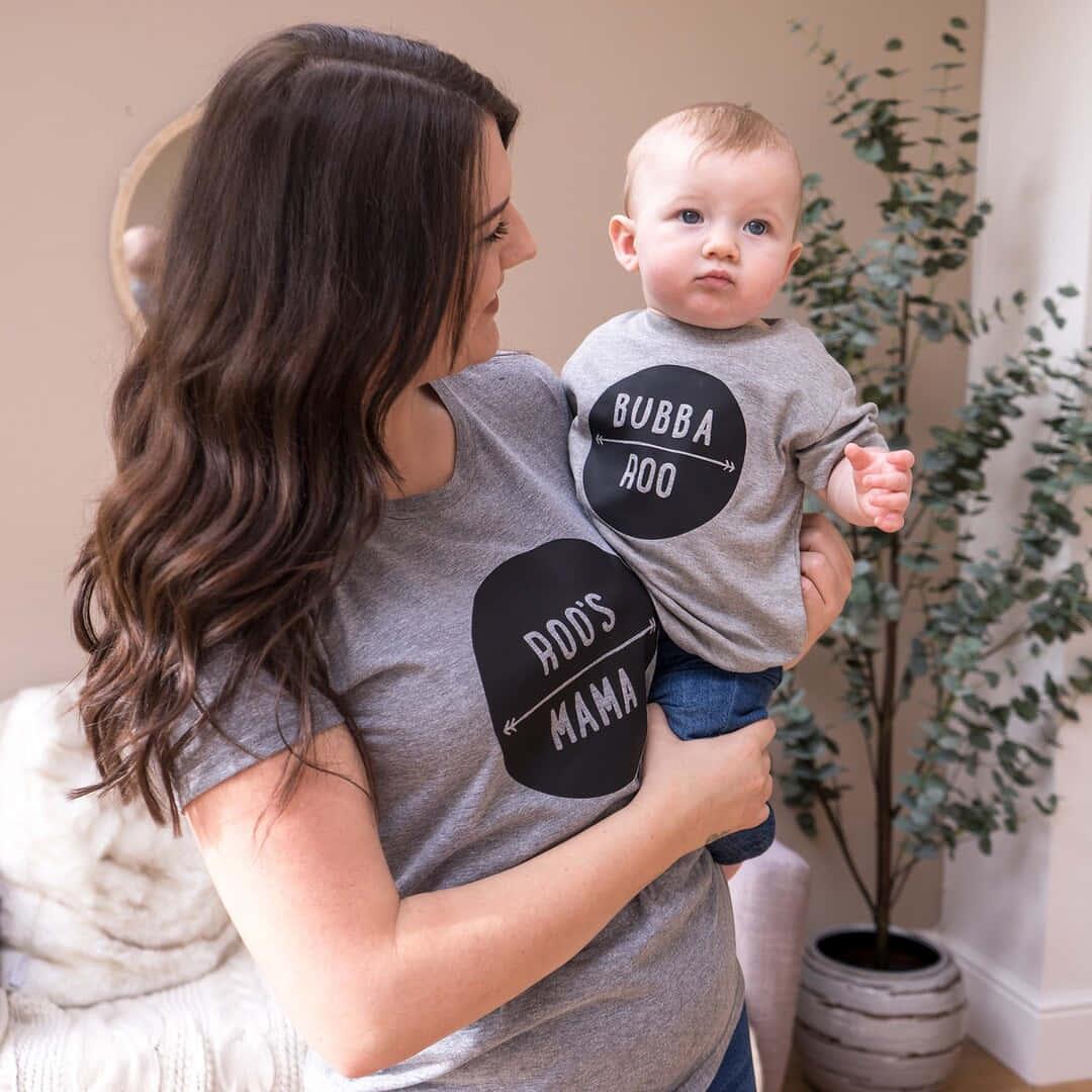 a woman holding a baby wearing a grey shirt that says dotty dotty mama — 1080x1080 wallpaper