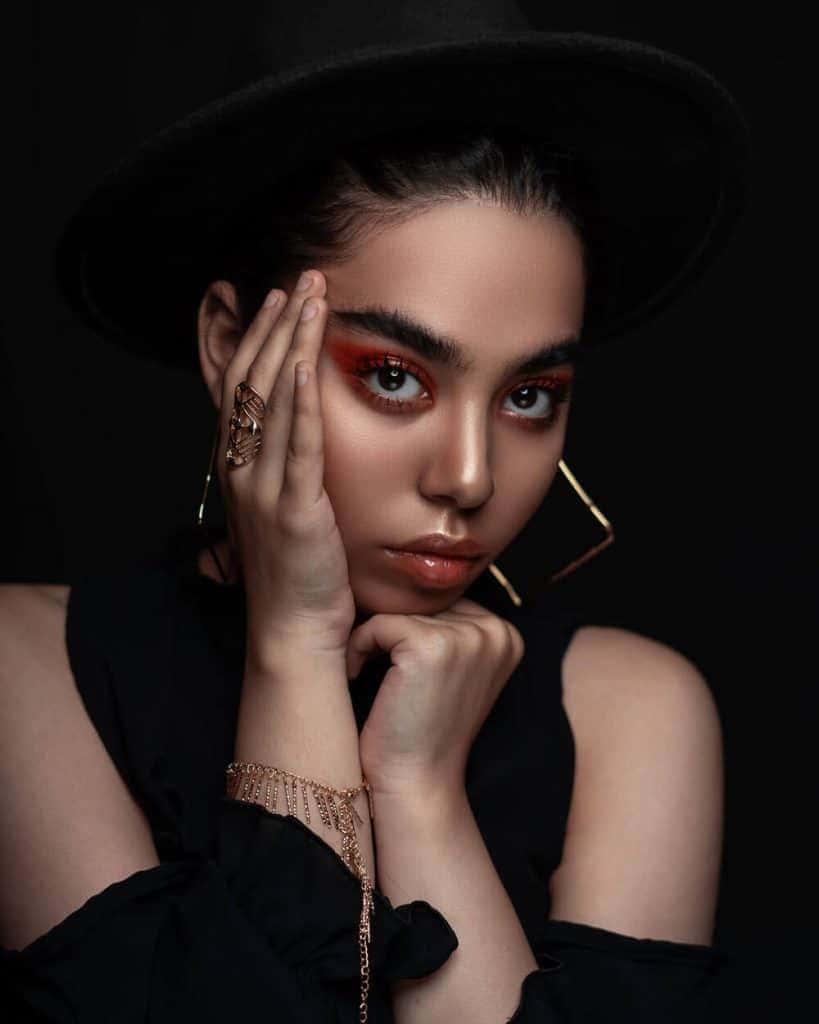 a woman in a black hat with gold jewelry — 819x1024 wallpaper